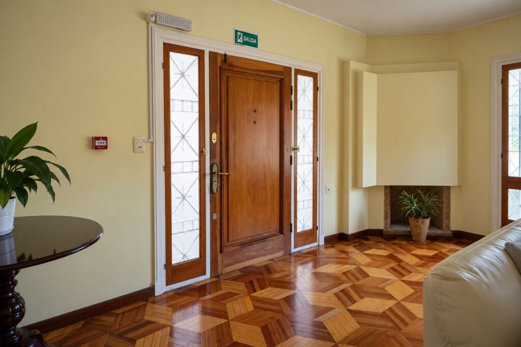 Hall de entrada con puerta de madera, vitrales y piso de parquet